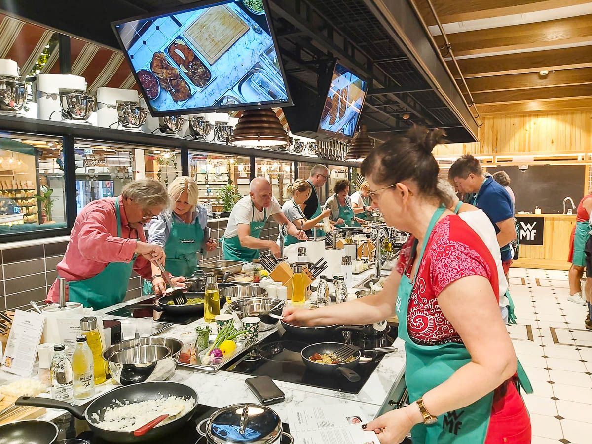 Deltakere lager mat på et lyst og stort kjøkken.